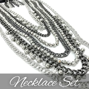 May include: A multi-layered necklace set featuring a mix of silver and gunmetal chains with beaded accents. The necklace set is a statement piece with a modern and edgy style.