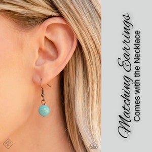May include: A close-up of a woman's ear wearing a pair of earrings with a turquoise stone and copper accents. The text "Matching Earrings Comes with the Necklace" is visible in the background.