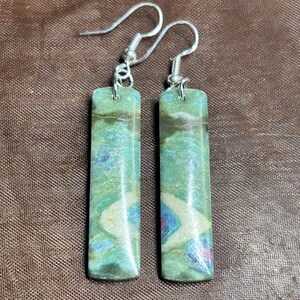 May include: A pair of silver earrings with green, blue, and white gemstone dangles. The gemstones are rectangular and have a marbled pattern.