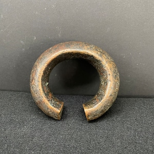 May include: A thick, circular, bronze bracelet with a worn, aged finish.