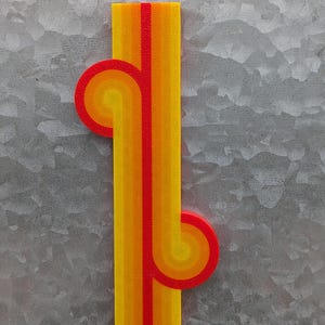 May include: A vertical, rectangular, multi-colored, abstract design with a red, orange, and yellow color scheme. The design features two curved, semi-circular shapes that are connected to the main rectangle.