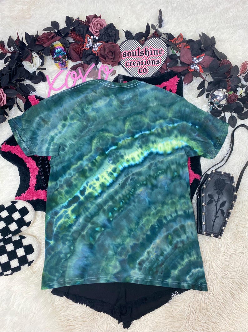 May include: Green tie-dye t-shirt with a swirling pattern. The shirt is made of a soft, comfortable material and has a relaxed fit.