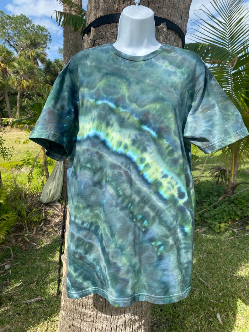 May include: A tie-dye t-shirt with a green, blue, and black swirl pattern. The shirt is made of a soft, comfortable fabric and has a crew neck.