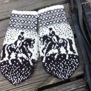 Könnte beinhalten: Ein Paar gestrickte Handschuhe in Schwarz und Weiß mit geometrischem Muster und einem Reiter-auf-Pferd-Motiv.