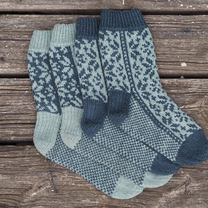 May include: Three pairs of knitted socks in shades of green and blue with a geometric pattern. The socks are folded and stacked on top of each other.
