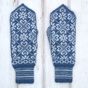 May include: A pair of blue knitted mittens with a white snowflake pattern. The mittens have a white cuff.