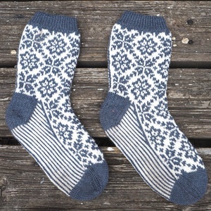 May include: A pair of blue and white knitted socks with a snowflake pattern. The socks are made with a striped pattern on the lower leg.