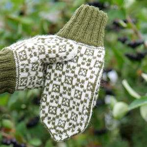 May include: A pair of knitted mittens with a white and green geometric pattern. The mittens are made of wool and have a green cuff.