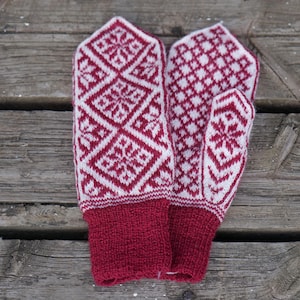 Könnte beinhalten: Ein Paar rote und weiße Strickhandschuhe mit geometrischem Muster. Die Handschuhe haben einen roten Bund.
