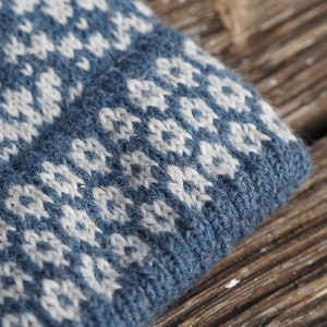 May include: Close-up of a blue and white knitted fabric with a geometric pattern. The fabric is soft and textured, with a fuzzy appearance.
