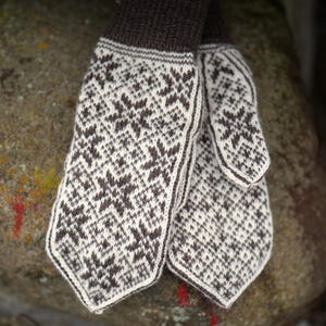 Peut inclure: Une paire de mitaines en laine tricotées de couleur marron et blanche avec un motif géométrique. Les mitaines sont douces et chaudes.