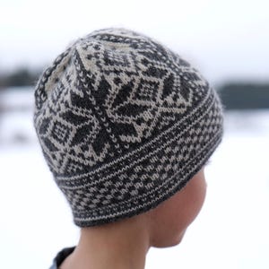 K&ouml;nnte beinhalten: Eine gestrickte M&uuml;tze in Schwarz und Wei&szlig; mit geometrischem Muster.