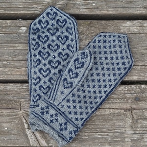Könnte beinhalten: Ein Paar graue und blaue Strickhandschuhe mit geometrischem Muster. Die Handschuhe liegen auf einer Holzoberfläche.