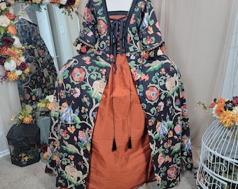 May include: A historical-style gown on a mannequin. The gown features a black floral patterned jacket over a rust-colored skirt. The jacket has a square neckline and is laced up the front. The sleeves have decorative trim. The text "Being Sew Weird" is visible.