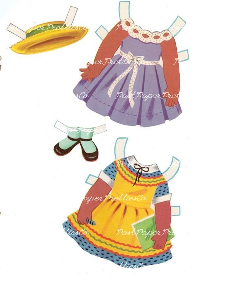 May include: A vintage paper doll set with a brown-skinned doll and two outfits. The first outfit is a purple dress with a white bow and white polka dots. The second outfit is a yellow dress with a blue and white polka dot pattern, a green book, and a red, yellow, and green trim.