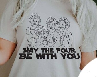 May include: A white t-shirt with a black and white illustration of four women. The text "May the four be with you" is printed below the illustration.