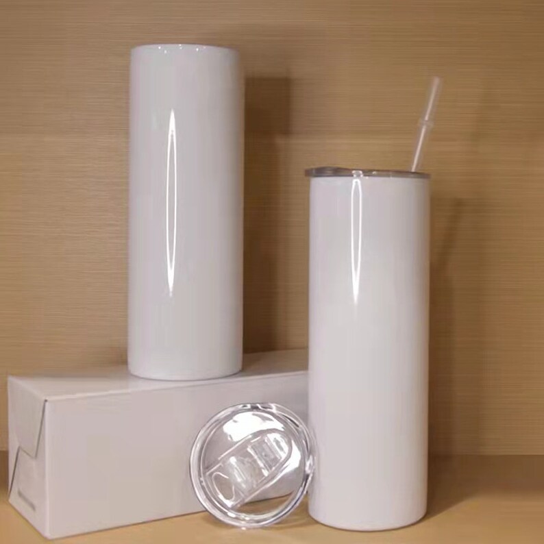 May include: Two white sublimation tumblers with lids and a straw. The tumblers are on a white box with a clear lid.