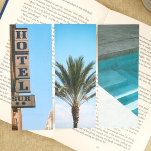 May include: A collage of three images: a hotel sign with the word "HOTEL" and "SUR", a palm tree against a blue sky, and a pool with steps. The images are layered over an open book.