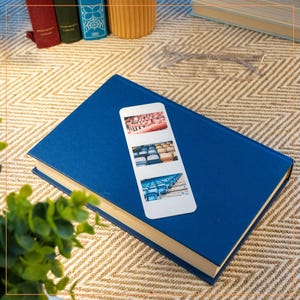 May include: A white bookmark with a collage of three photos of stadium seating. The photos show rows of blue and red seats.
