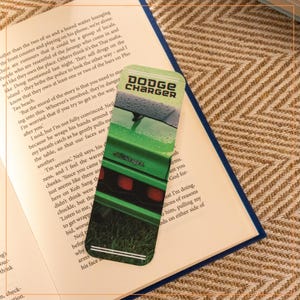 May include: A green Dodge Charger bookmark with raindrops on the windshield. The bookmark has a white border and the words "Dodge Charger" in white text.