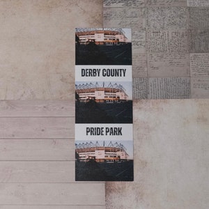 Puede incluir: Una impresión en blanco y negro con una imagen de un estadio y el texto "Derby County" y "Pride Park".