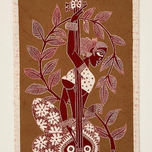 May include: A rectangular textile wall hanging featuring a brown batik background with a white border. The design depicts a figure playing a stringed instrument, surrounded by stylized leafy branches. The figure wears patterned clothing.