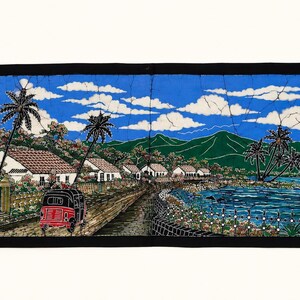 Könnte beinhalten: Ein rechteckiger Batik-Wandbehang mit einer Küstendorf-Szene, weißen Häusern, Palmen und einem roten dreirädrigen Fahrzeug auf einer Straße. Die Landschaft umfasst ein blaues Meer, grüne Berge und einen hellblauen Himmel mit weißen Wolken.