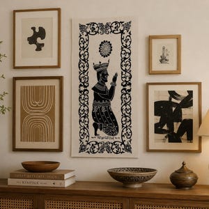 Può includere: Una parete di galleria con opere d'arte incorniciate e oggetti decorativi. Le opere d'arte includono stampe astratte e un'illustrazione in bianco e nero di una figura. Una console in legno contiene libri, ciotole e una lampada.