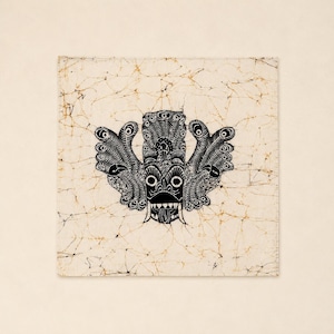 May include: Square batik textile featuring a black, stylized mask design with large eyes, a wide mouth, and ornate feathered wings. The mask is centered on a cream-colored background with a network of brown lines.