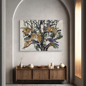 Op de afbeelding: Een rechthoekig wandkunstwerk met een gedetailleerde illustratie van meerdere vogels die op de takken van een donkere, gestileerde boom zitten. De vogels zijn weergegeven in tinten bruin, beige en blauw tegen een lichte, getextureerde gebroken witte achtergrond.