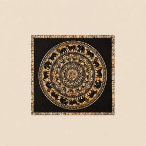 May include: A square textile featuring a black and gold batik pattern. The design consists of concentric circles with a central floral motif surrounded by rings of stylized elephants and other animals, all framed by a decorative border.