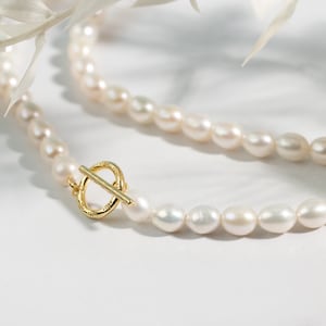 May include: A white pearl necklace with a gold clasp. The necklace is made of small, round pearls and is about 18 inches long.