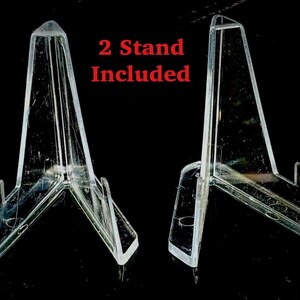 May include: Two clear acrylic display stands. The stands are triangular with a flat base and a support ledge. The text "2 Stand Included" is in red. The stands are on a black background.