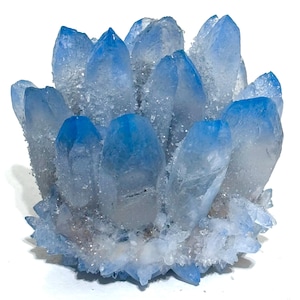 Pode incluir: Um aglomerado de pontas cristalinas com um gradiente de branco translúcido na base que transita para um azul vibrante nas pontas. A formação mineral consiste em múltiplas pontas verticais e irregulares com uma superfície texturizada.