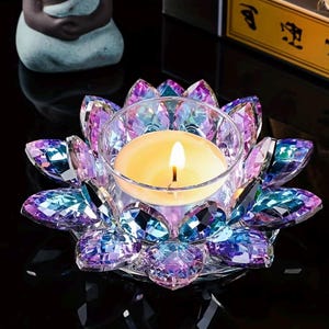May include: A crystal lotus flower candle holder with a lit candle. The holder has iridescent purple, blue, and clear crystal petals. The candle is in a clear glass cup.