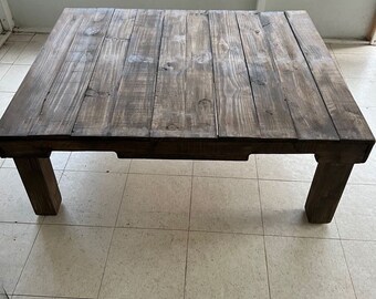 May include: A rustic wooden coffee table with a dark brown stain. The table has a rectangular top and four legs.