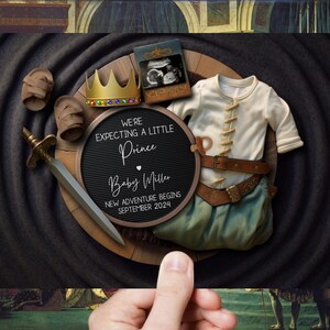 May include: A black and white announcement board with the text "We're expecting a little Prince Baby Miller New adventure begins September 2024". The board is surrounded by a crown, baby booties, a sword, and a baby outfit.