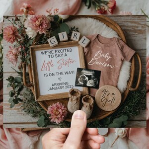 May include: A baby announcement card featuring a wooden tray filled with pink flowers, a pink onesie with the text "Baby Davison", a wooden sign that reads "We're excited to say a little sister is on the way! Arriving January 2025", a wooden sign that says "It's a girl!" and a small ultrasound image.