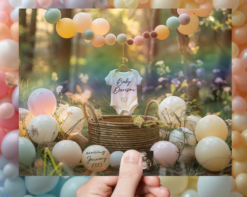 May include: A white onesie with the text "Baby Davison" and a heart design. The onesie is hanging on a clothesline with a string of pastel balloons in the background. The balloons are pink, peach, yellow, and blue. There is a basket of pastel colored balloons in the foreground.