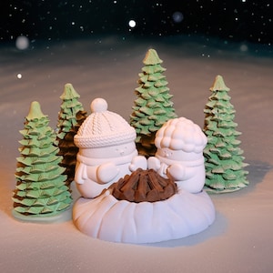May include: Two white ceramic snowmen figurines with painted details, sitting around a brown campfire, surrounded by four small green Christmas trees.