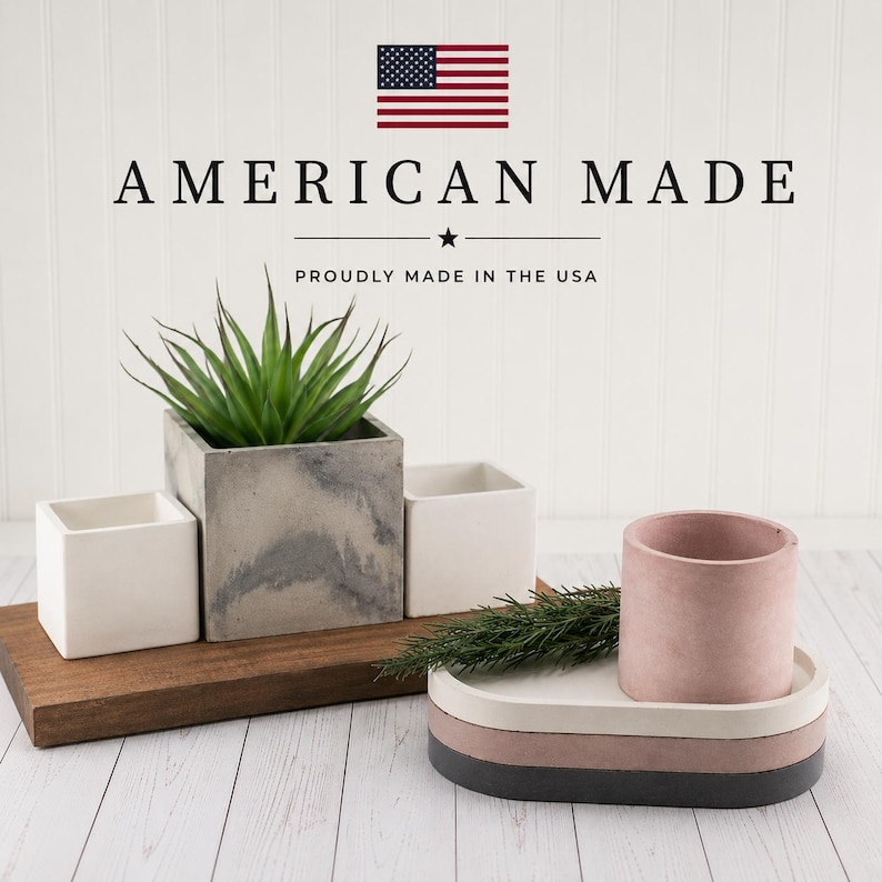 May include: A set of concrete planters and trays including a large grey marbled square planter with a green succulent, two small white square planters, and a pink cylindrical planter on a stacked oval tray with white, pink, and dark grey layers.