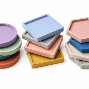 May include: A collection of colorful trays in various shapes: round, square, and hexagonal. The trays are in shades of purple, teal, green, orange, gray, light blue, peach, yellow, blue, and a marble pattern. They are stacked in small piles.