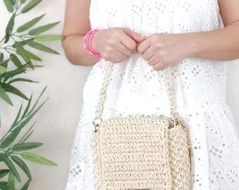 May include: A beige crocheted shoulder bag with a gold chain strap. The bag has a flap closure and a gold metal accent.