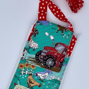 May include: A quilted fabric pouch with a red polka dot strap and trim. The pouch features a farm scene with a red tractor, sheep, chickens, and the text "Farm Chick". The background is teal with white stitching.