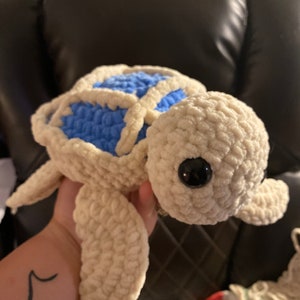 May include: A crocheted stuffed sea turtle toy with a white shell and blue underbelly. The turtle has large black eyes and a soft, plush texture.