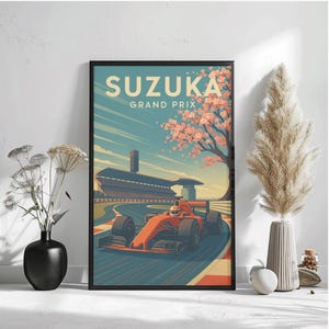 Puede incluir: Lámina enmarcada con una ilustración de estilo vintage del Gran Premio de Suzuka. La obra de arte muestra un coche de carreras rojo en una pista, con el texto "SUZUKA GRAND PRIX". El fondo incluye un edificio, un cerezo en flor y un cielo azul.
