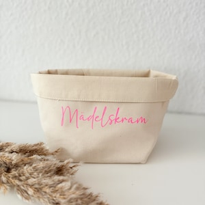 Könnte beinhalten: Ein weißer Stoffaufbewahrungskorb mit pinker Aufschrift "Mädlskram".