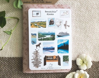 May include: A set of 12 stickers featuring illustrations of Alaskan scenery, wildlife, and landmarks. The stickers are printed on white paper with a glossy finish. The stickers include images of mountains, a river, a cruise ship, a moose, a polar bear, a sea otter, and a sign that says "Welcome to Alaska".