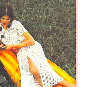 May include: A white crochet maxi skirt with a side slit. The skirt is worn by a woman lying on a yellow and orange striped blanket in a grassy field.