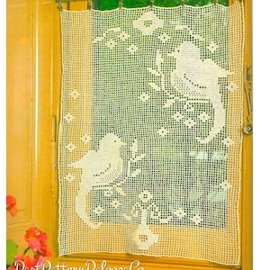 Puede incluir: Una cortina de crochet blanca con un diseño de pájaro. La cortina está colgada en una ventana con un marco amarillo. El texto "PastPatternPaloozaCo" es visible en la esquina inferior izquierda de la imagen.